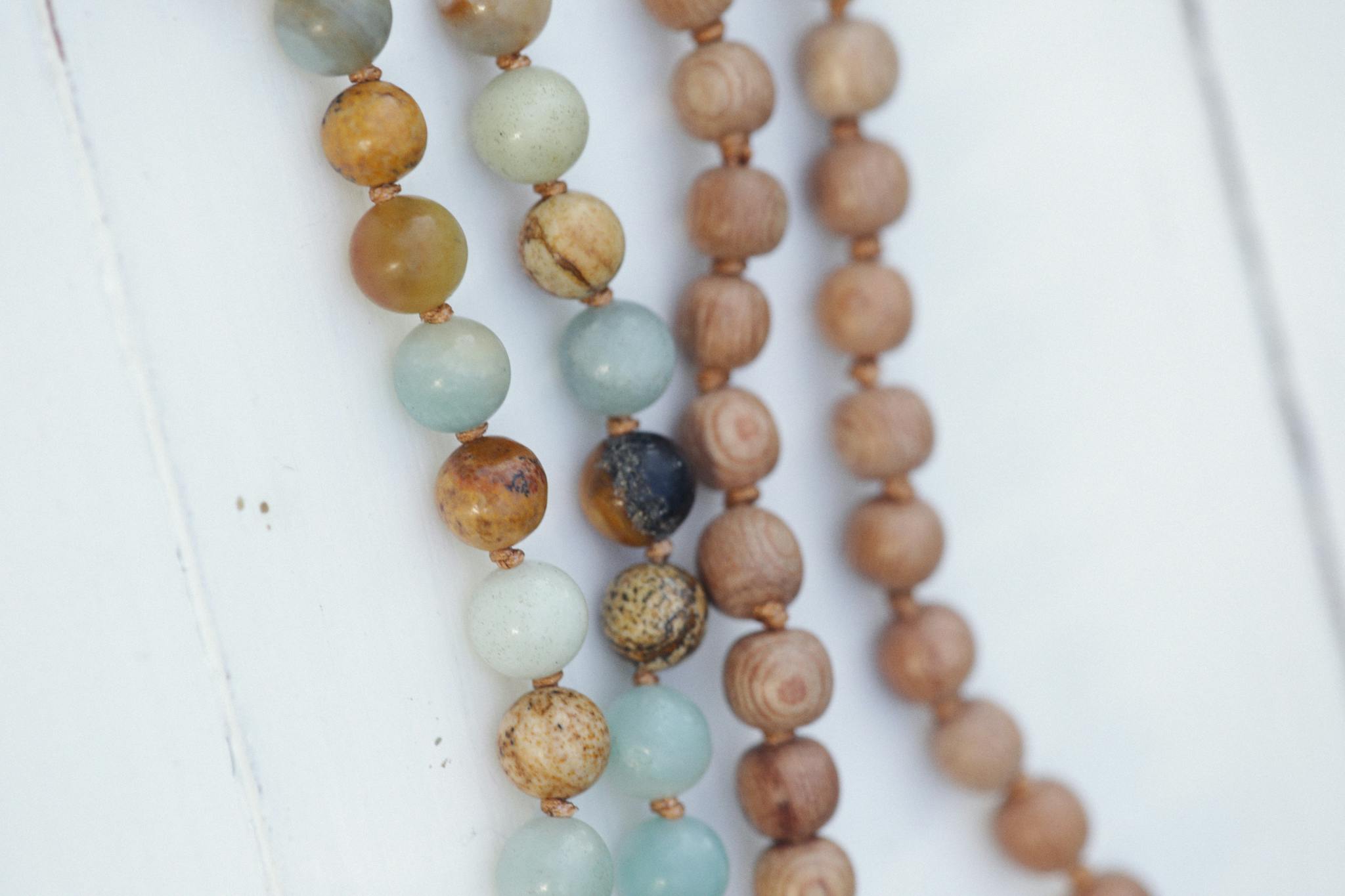 A close-up view of colorful beaded necklaces on a smooth white surface, showcasing texture and craftsmanship.