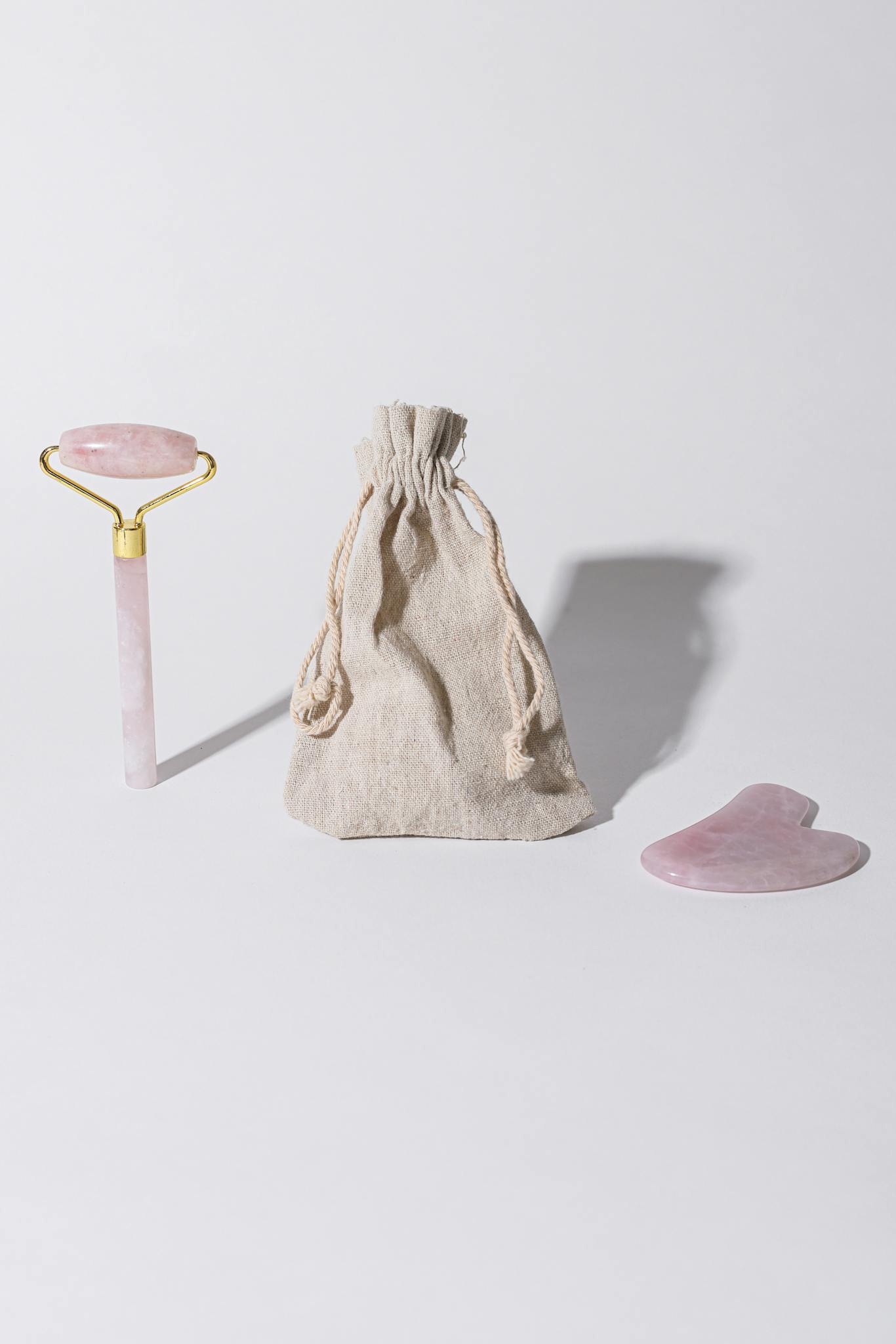 A minimalist setup featuring a jade roller, gua sha, and pouch on a white background.